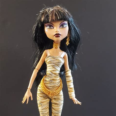 Cleo de nile doll original - Sold Out. The Monster High Haunt Couture collection features the original Monster High ghouls wearing hauntingly chic, runway-ready renditions of their iconic looks. Inspired by her royal scaritage, Cleo De Nile doll wears a golden metallic mummy wrap adorned with cryptacular chic accessories.